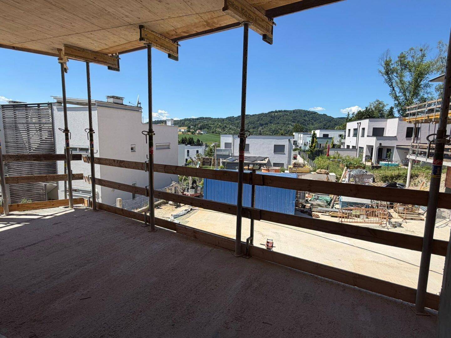 Blick von einem Rohbau-Balkon auf die umliegende Baustelle und moderne Neubauten.
