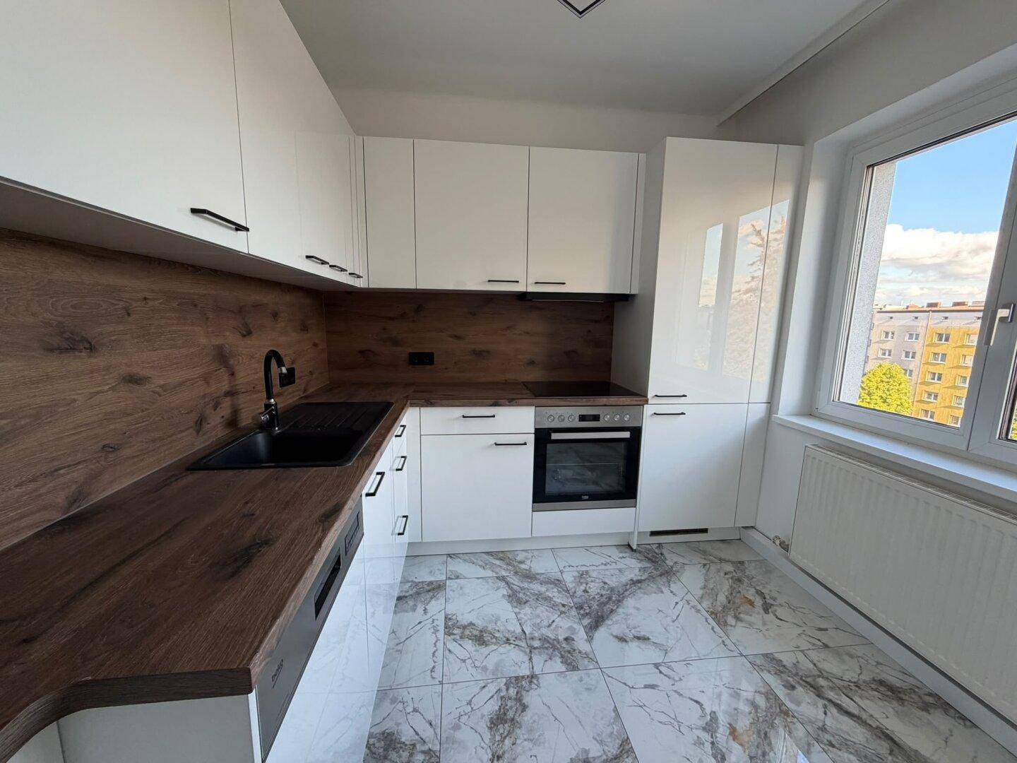 Moderne Küche mit weißen Hochglanzschränken, Holzoptik-Arbeitsplatten und Marmorfliesenboden.