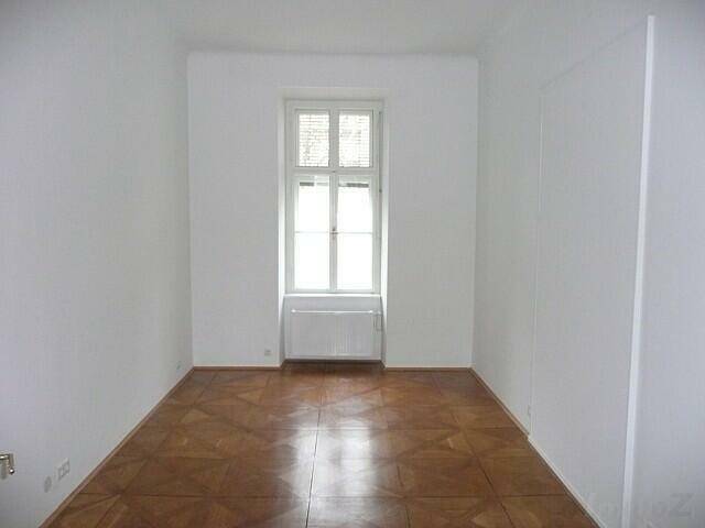 Gemütliches Zimmer mit Parkettboden und einem großen Fenster, ideal als Schlaf- oder Arbeitszimmer.