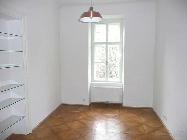 Helles Zimmer mit Parkettboden, Einbauregalen und einem Fenster, perfekt als Büro oder Bibliothek.