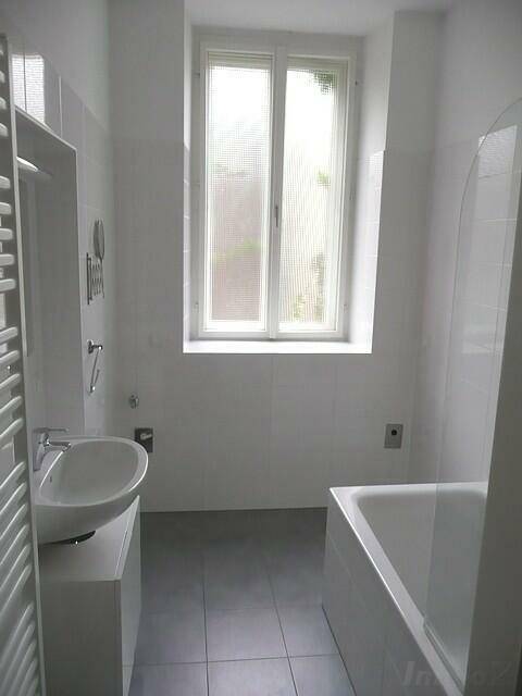 Helles Badezimmer mit Badewanne, Waschbecken und einem Fenster für natürliche Belüftung.