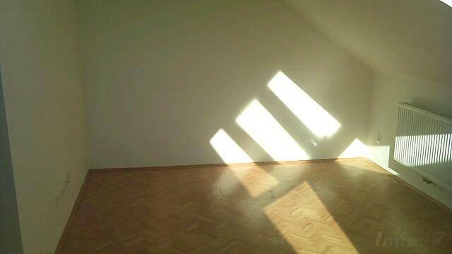 Heller Raum mit Fischgrätparkettboden, Dachschräge und viel natürlichem Licht.