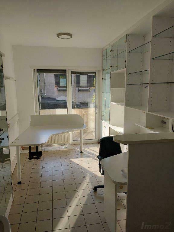 Heller Büroraum mit Fliesenboden, großen Fenstern und integrierten Regalen, ideal für Arbeitszwecke.