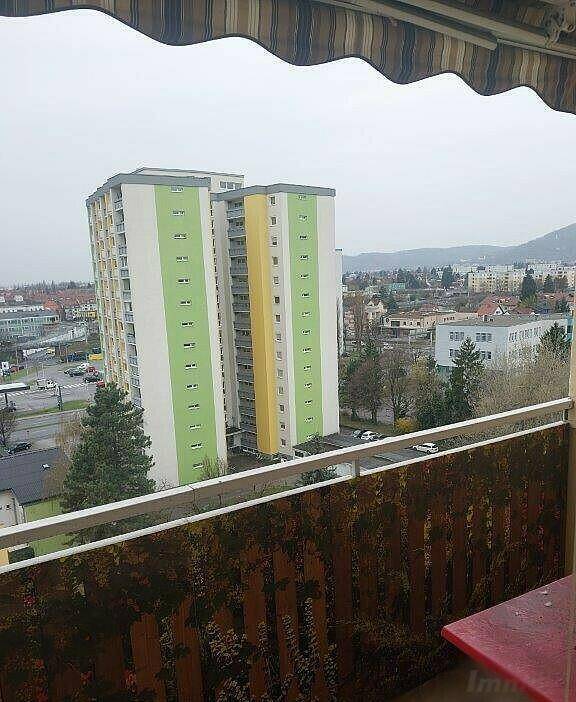 Weitblick von einem Balkon über die Stadt mit hohen Wohngebäuden und Bergen am Horizont.