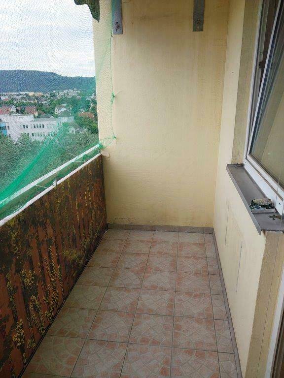 Gefliester Balkon mit Schutznetz und Blick auf die Stadt und die umliegenden Hügel.
