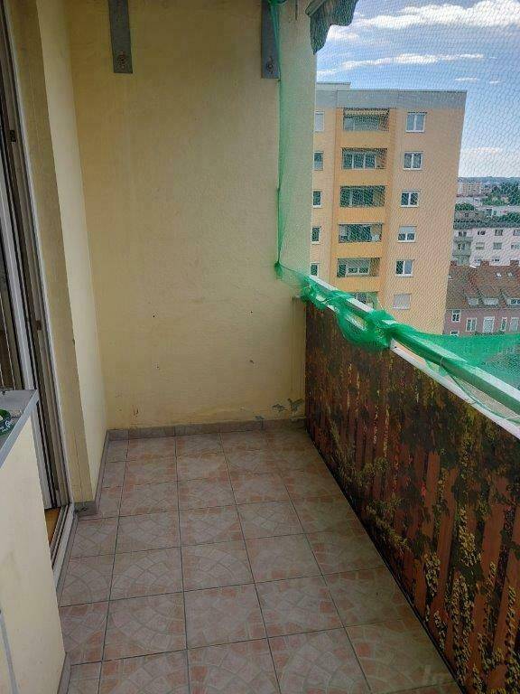 Gefliester Balkon mit Schutznetz und Blick auf die Stadt und ein weiteres Wohngebäude.