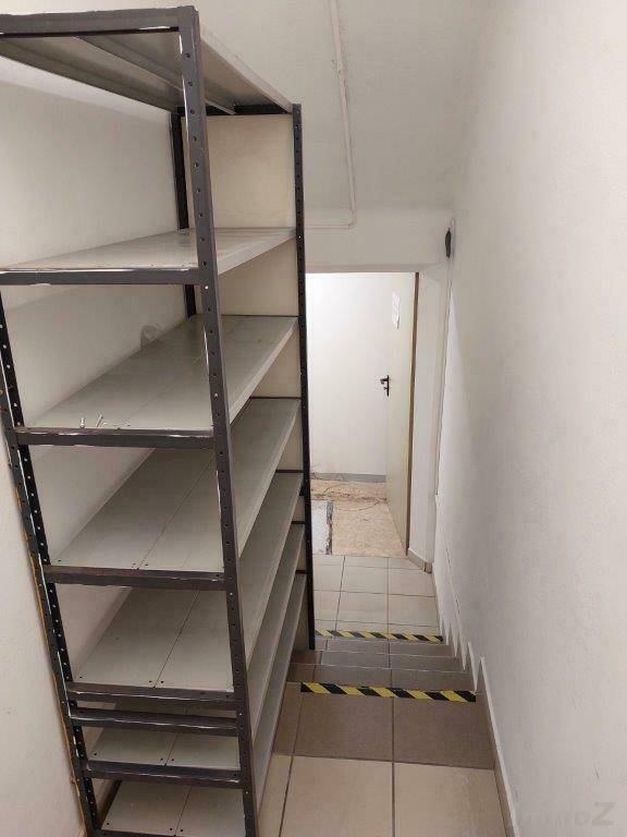 Kellertreppe mit Metallregal und Fliesenboden, die nach unten führt.