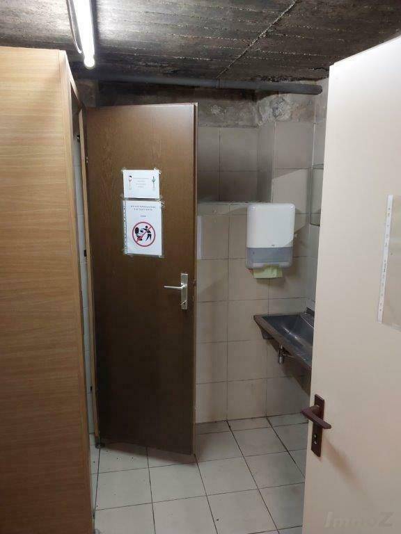 Einfache Gästetoilette im Keller mit Waschbecken und Handtuchspender.