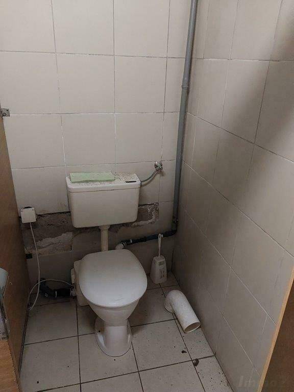Keller-Gästetoilette mit WC, Fliesen und sichtbaren Installationsspuren.