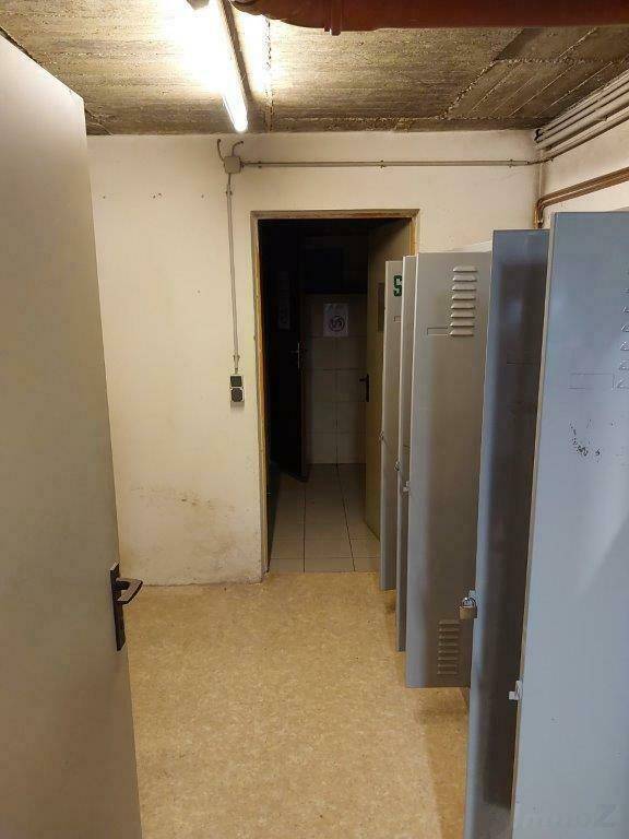 Umkleideraum im Keller mit Spinden und einem Durchgang zu weiteren Räumen.