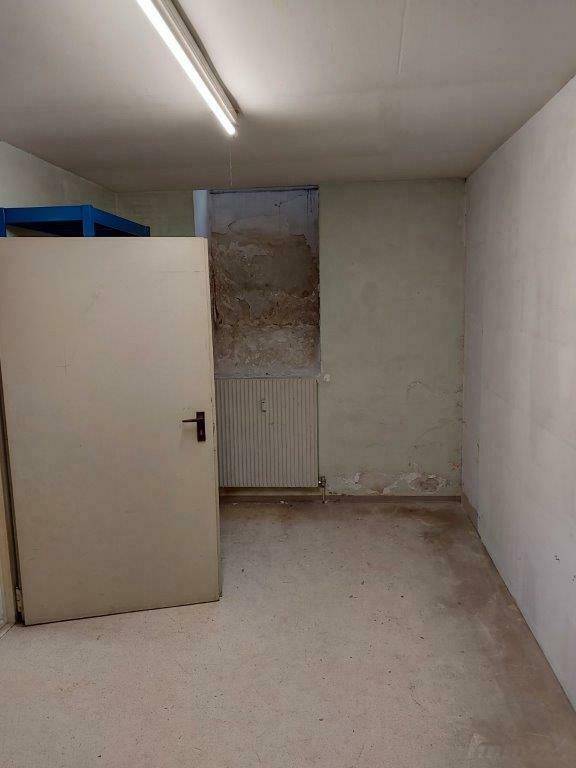 Kellerraum mit einfacher Tür, Heizkörper und sichtbaren Wandunebenheiten.