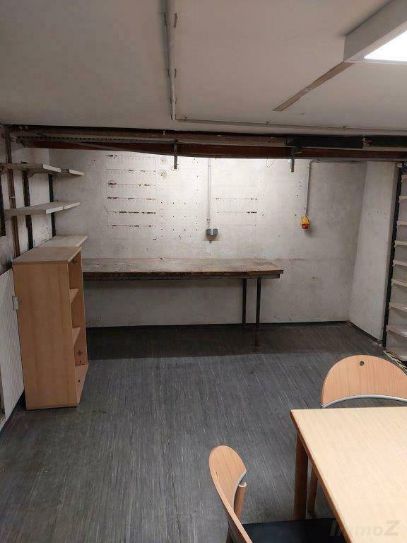 Kellerbüro mit Tisch, Stühlen und Regalen, ideal für Werkstatt oder Lager.