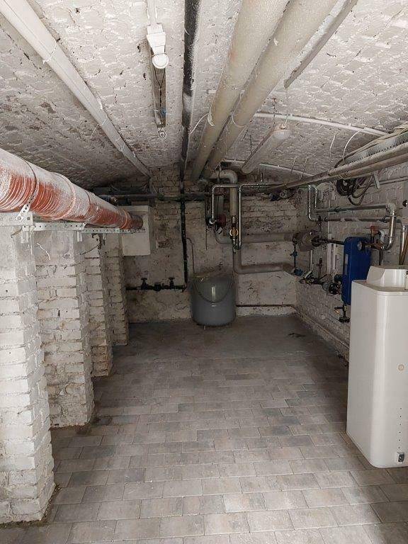 Heizungsraum im Keller mit technischen Installationen und Ziegelwänden.