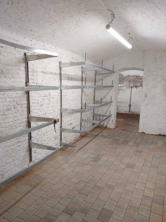Kellerraum mit Regalsystemen an der Wand und Fliesenboden.