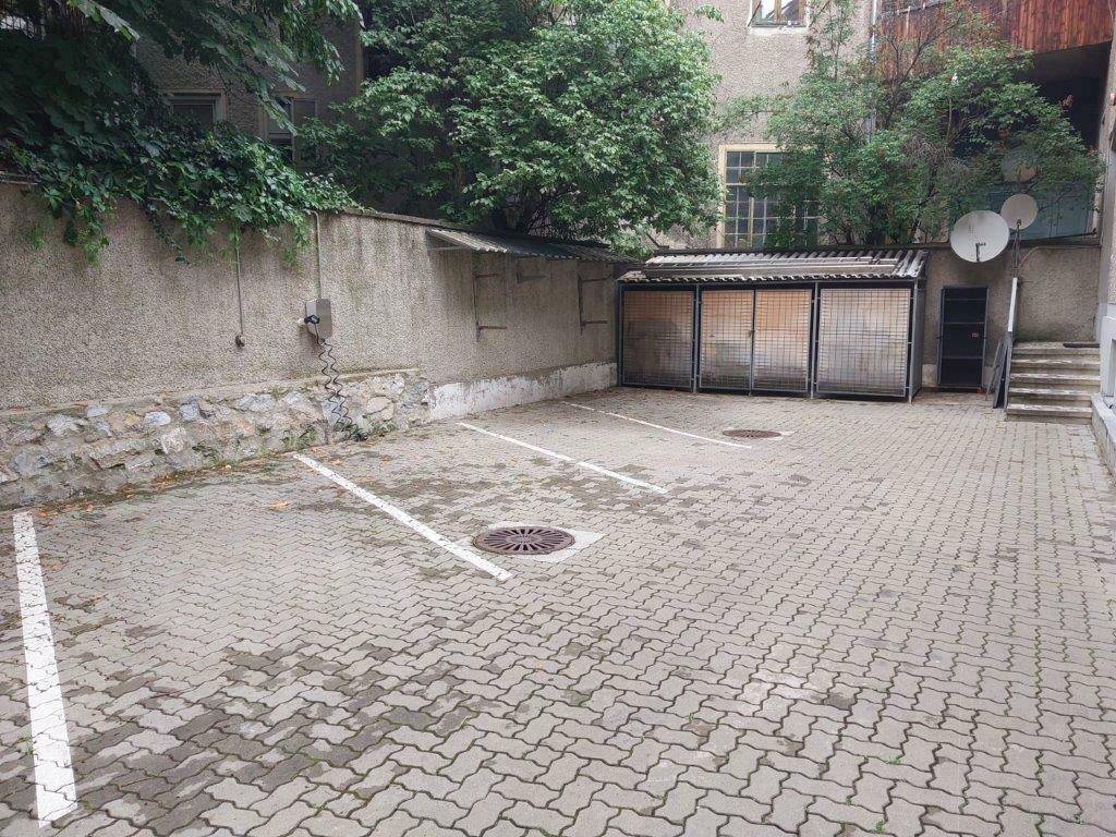 Gepflasterter Innenhof mit markierten Parkplätzen und einem Fahrradunterstand im Hintergrund.