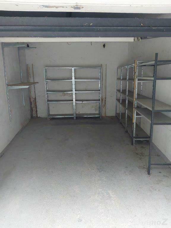 Geräumige Garage mit Betonboden und Metallregalen für Lagerzwecke.