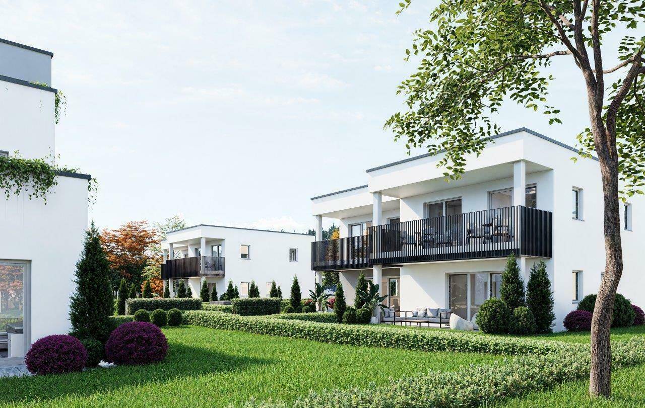 Moderne Wohngebäude mit Balkonen und gepflegten Gärten, umgeben von Bäumen und Grünflächen.