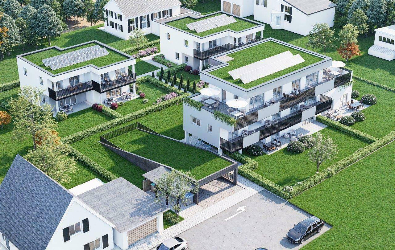 Luftaufnahme einer modernen Wohnanlage mit begrünten Dächern, Balkonen und gepflegten Gärten.