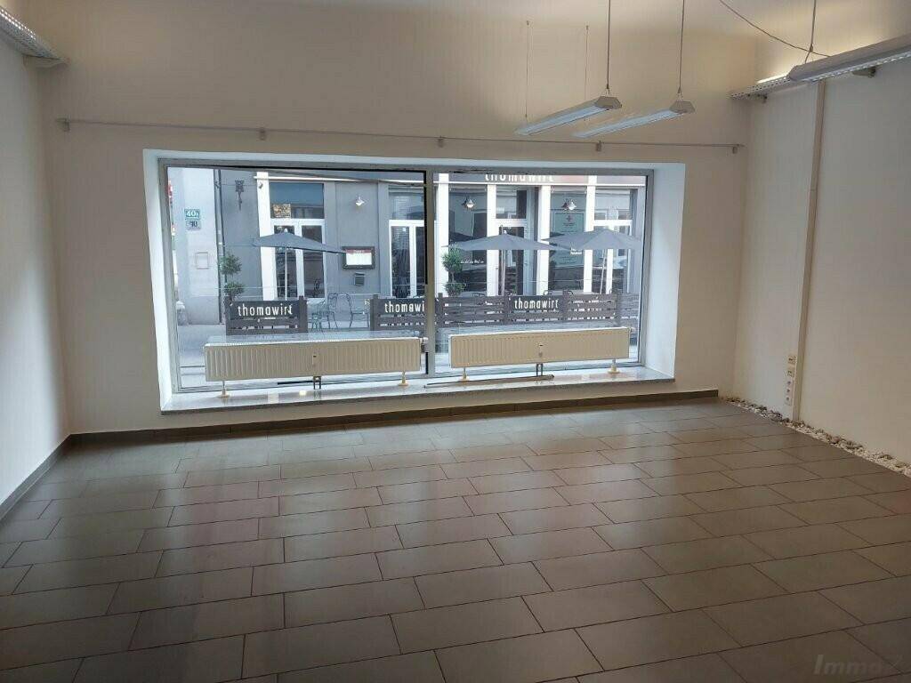 Heller Gewerberaum mit großen Schaufenstern, Fliesenboden und Blick auf die belebte Straße, ideal für ein Ladenlokal.