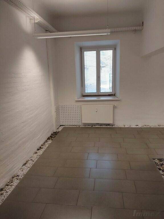 Helles Büro mit Fliesenboden, Fenster und strukturierten Wänden, bietet eine angenehme und funktionale Arbeitsatmosphäre.