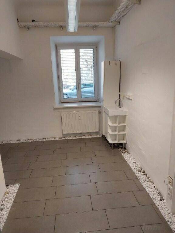 Kleiner Büroraum mit Fenster, Heizkörper und einer kompakten Spüleinheit, ideal für eine Teeküche oder Arbeitsbereich.