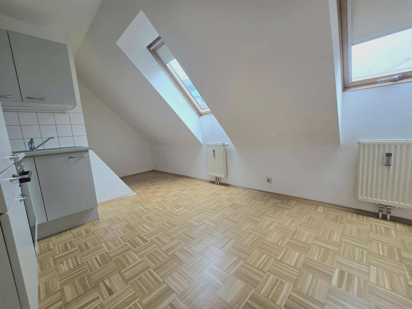 Helle Küche mit Dachschrägen, Parkettboden und zwei Dachfenstern.