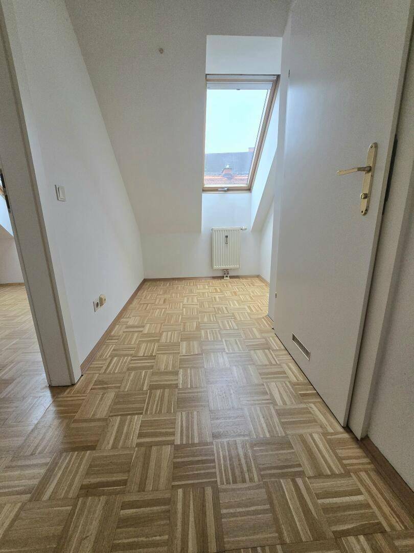 Heller Flurbereich mit Parkettboden, Dachschräge und Dachfenster.