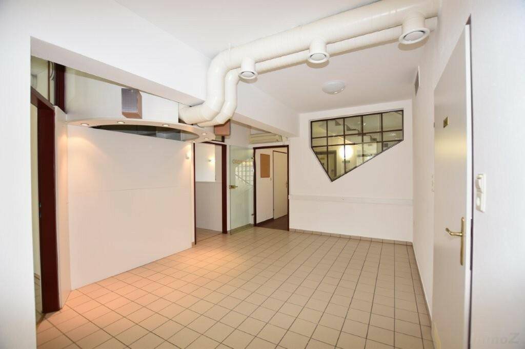 Geräumiger Flur oder Empfangsbereich mit Fliesenboden, sichtbaren Leitungen und ungewöhnlichem Fensterdesign.