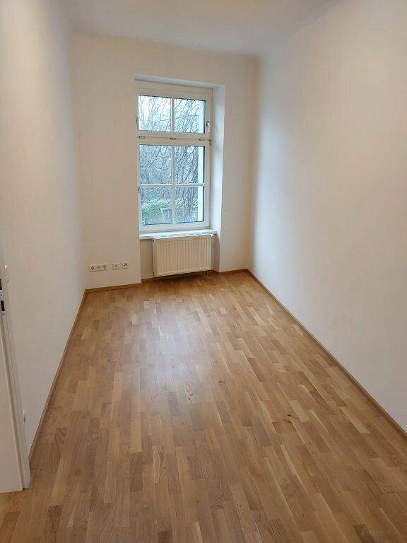 Gemütliches Zimmer mit Parkettboden und einem großen Fenster, ideal als Schlaf- oder Arbeitszimmer.