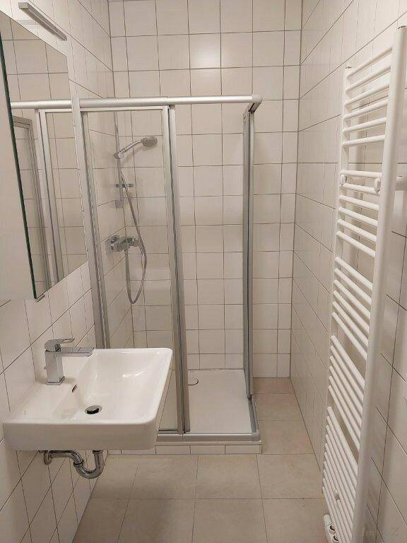 Modernes Badezimmer mit Duschkabine, Waschbecken und weiß gefliesten Wänden.
