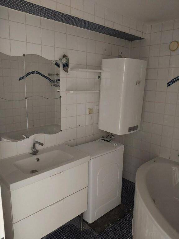 Badezimmer mit Waschbecken, Waschmaschine, Boiler und Eckbadewanne.