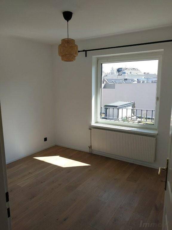 Helles Schlafzimmer mit Parkettboden, einem Fenster und viel natürlichem Licht.