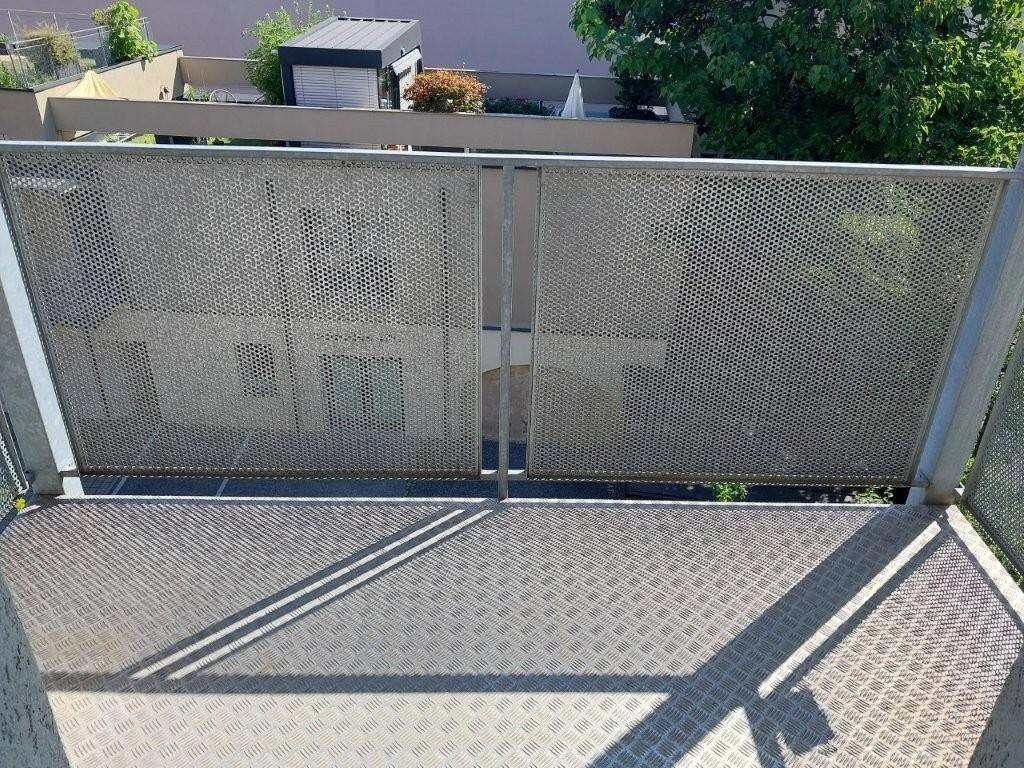 Balkon mit rutschfestem Metallboden und perforiertem Geländer.