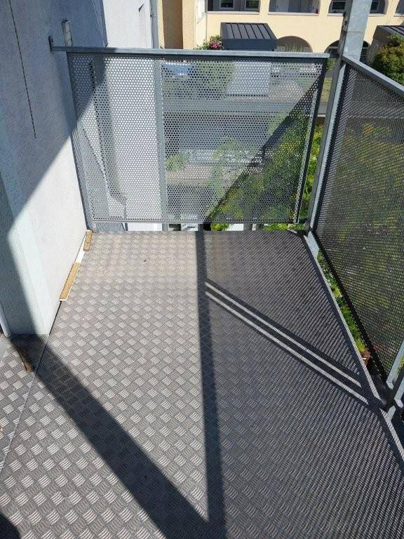 Ecke eines Balkons mit Metallgeländer und Blick auf die Umgebung.