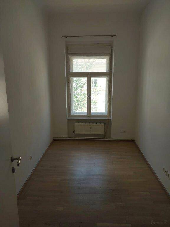 Geräumiger, leerer Raum mit Holzboden, Fenster und viel natürlichem Lichteinfall, gut erhalten.