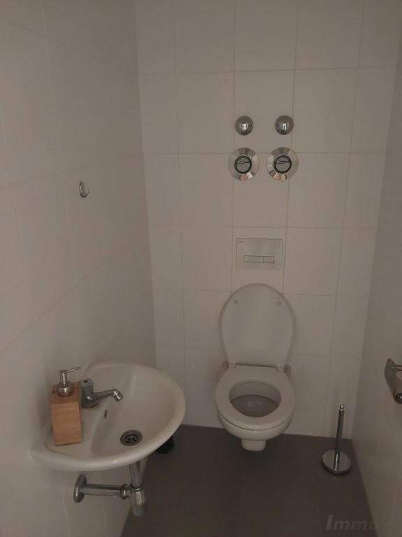 Separate Toilette mit Waschbecken, wandmontiertem WC und weißen Wandfliesen.