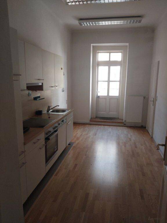 Schmale Küche mit heller Einbauküche, Holzfußboden und Zugang zu einem Balkon oder Terrasse.