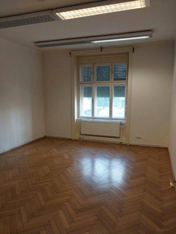 Lichtdurchflutetes Zimmer mit elegantem Fischgrätparkett und einem großen Fenster.