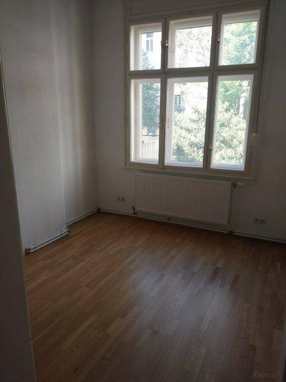 Helles Zimmer mit Laminatboden und einem großen Fenster mit Blick ins Grüne.