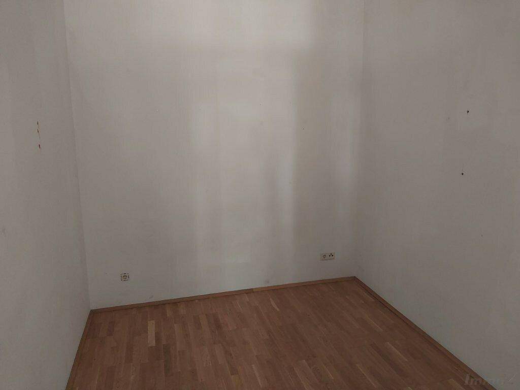 Leerer Raum mit hellem Laminatboden und weißen Wänden, bereit zur individuellen Gestaltung.