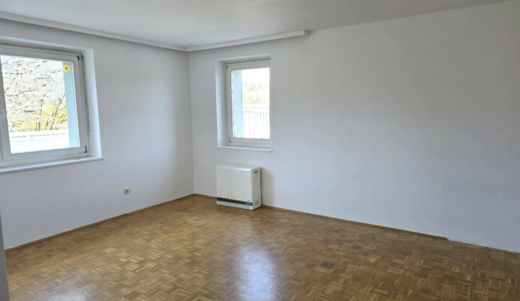 Helles Zimmer mit Parkettboden und zwei Fenstern, ideal als Schlaf- oder Arbeitszimmer.