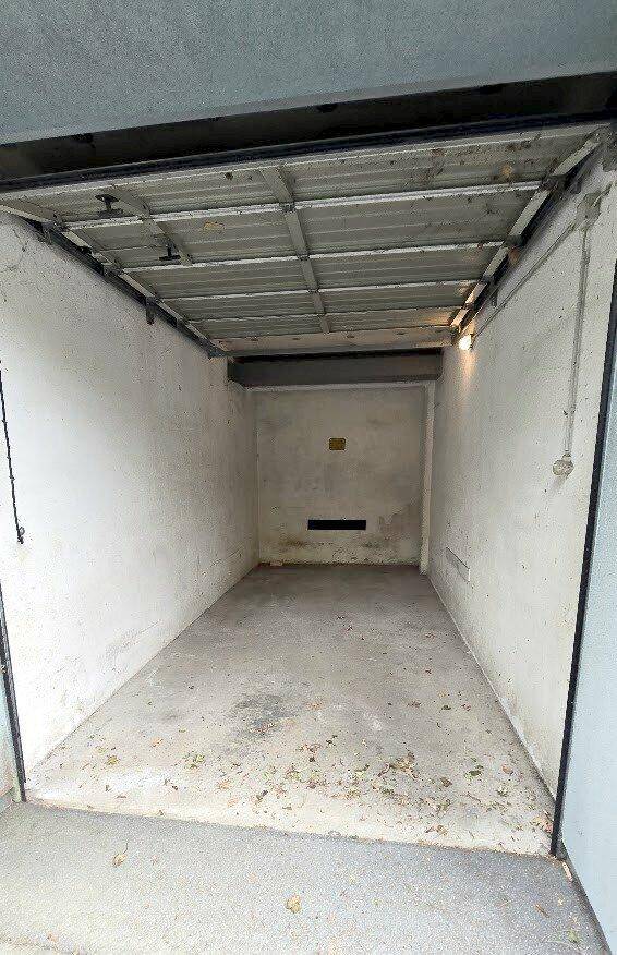 Leere Garage mit Betonboden und Rolltor, bietet Platz für ein Fahrzeug.