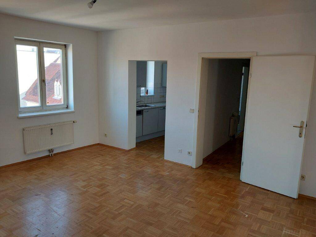 Heller Wohnraum mit Parkettboden und Durchgang zur Küche, ideal für offenes Wohnen.