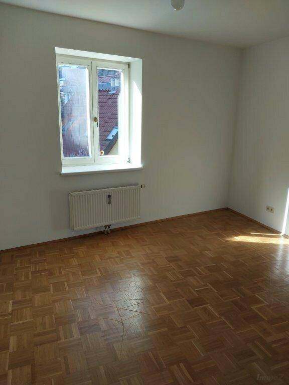 Heller Raum mit Parkettboden und einem Fenster, ideal als Schlaf- oder Arbeitszimmer.