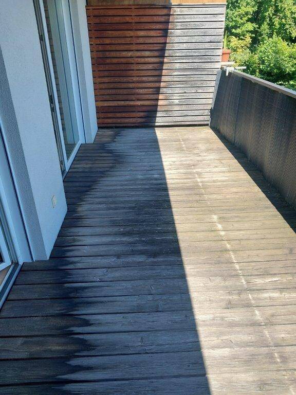 Geräumiger Balkon mit Holzdielen und seitlichem Sichtschutz, ideal für Entspannung im Freien.