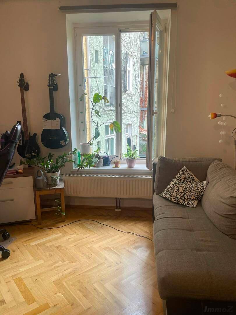 Helles Wohnzimmer mit Parkettboden, Sofa und Blick ins Grüne.