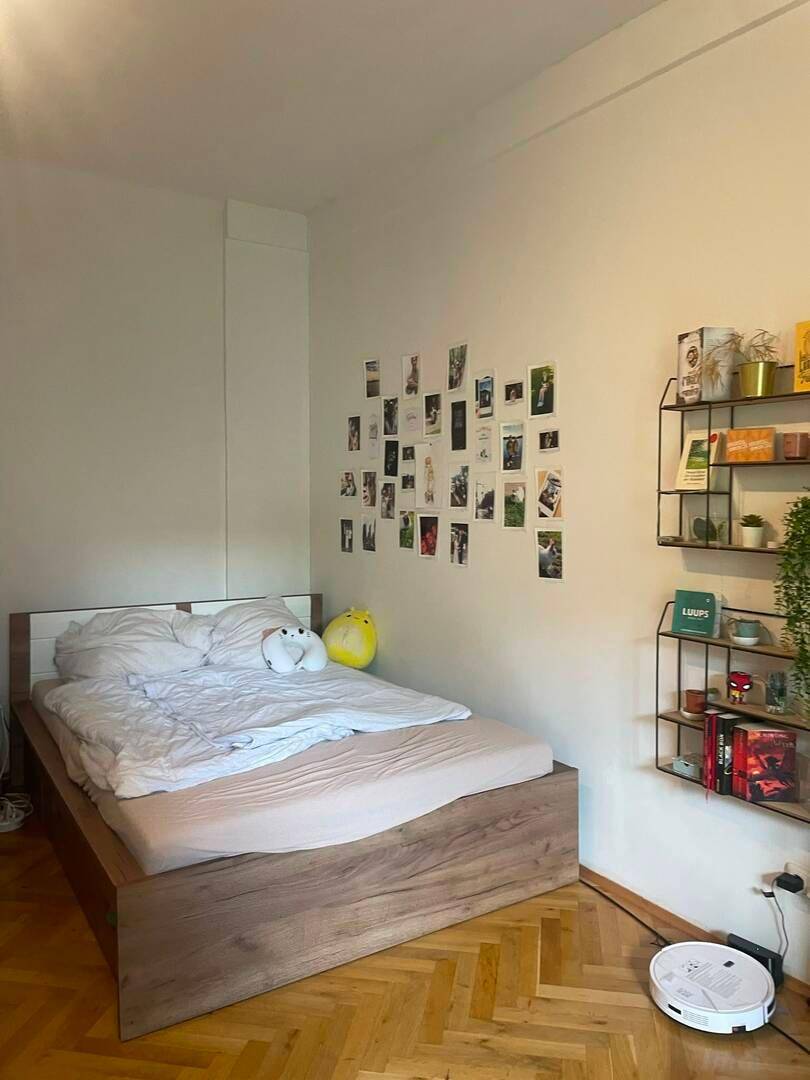 Schlafzimmer mit Holzbett, Parkettboden und einfacher Dekoration.