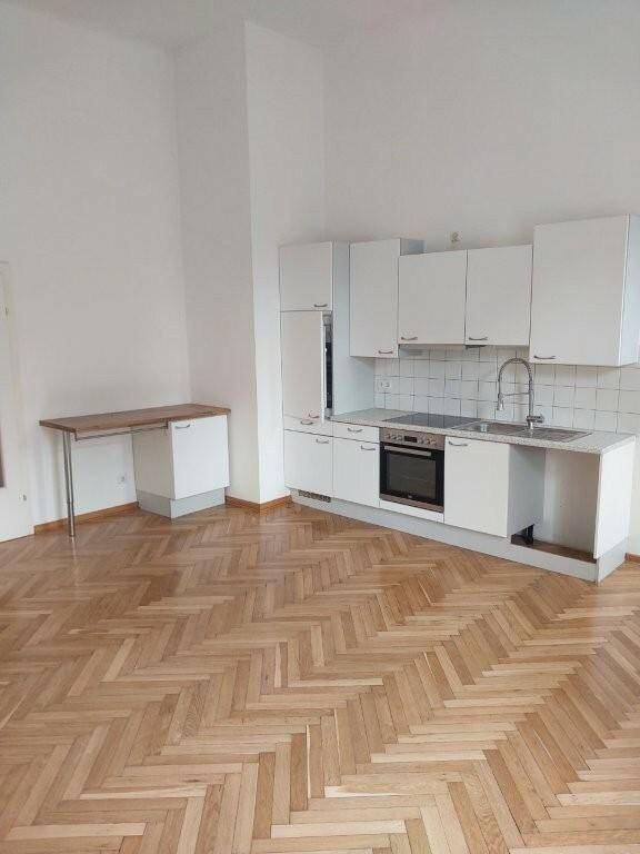 Funktionale weiße Küchenzeile mit integriertem Backofen und Arbeitsplatte in einem hellen Raum.
