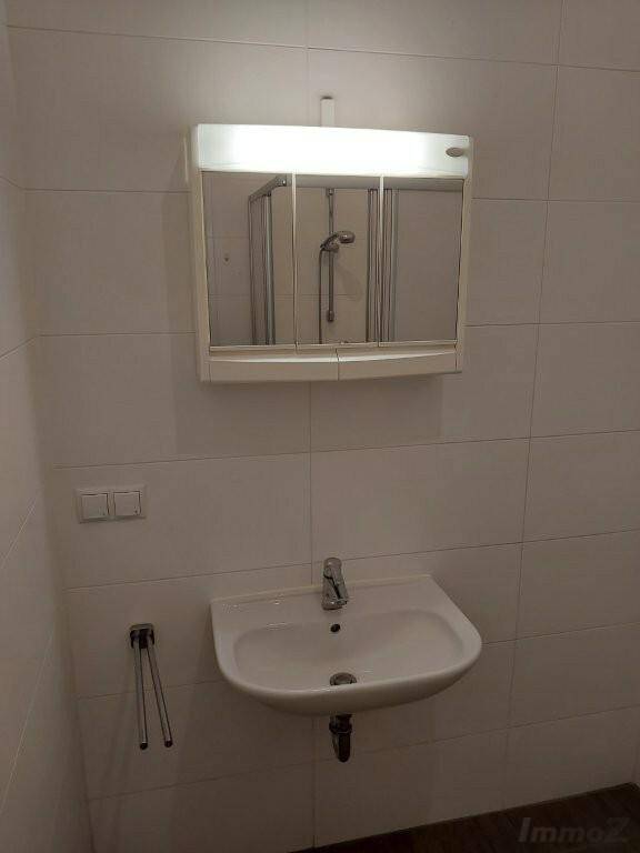 Helles Badezimmer mit Waschbecken, Spiegelschrank und weißen Fliesen.