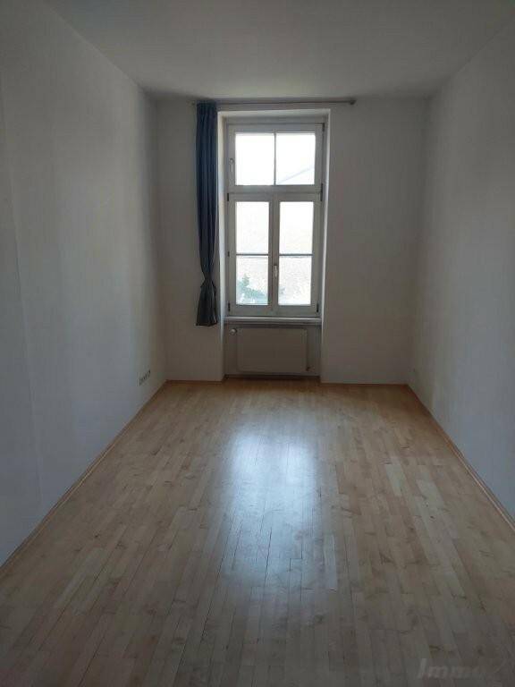 Heller Raum mit hellem Laminatboden und einem großen Fenster, bietet viel Tageslicht.